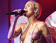 Miley Cyrus almost topless perform on a stage